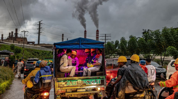 Nickel industry workers rides a modified mini pick-up used as a local public transport in Halmahera island, North Maluku, Indonesia, amidst local traffic congestion and smoldering chimneys of nickel smelting and processing plant, August 2024. (CGSP / Mas Agung Wilis Yudha Baskoro)