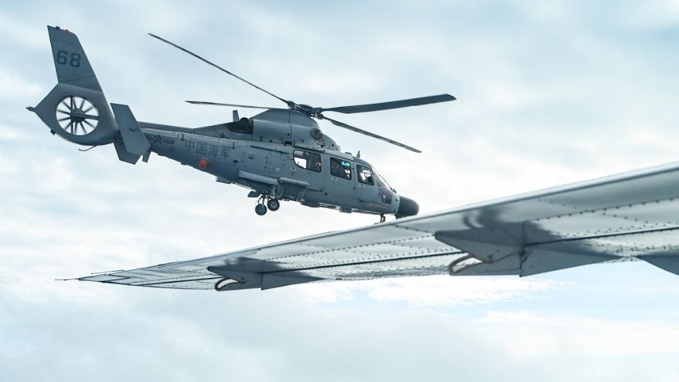 An aircraft identified by the Philippine Coast Guard as Chinese Navy helicopter (L) flies near the Bureau of Fisheries and Aquatic Resources (BFAR) plane during an aerial reconnaissance flight at Scarborough Shoal in the South China Sea on February 18, 2025.