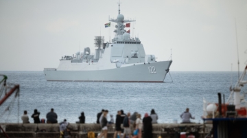 People on Kalk Bay fishing harbour as the Chinese guided-missile destroyer Tangshan (Hull 122) is moored in False Bay, close to Simon's Town, near Cape Town, on January 6, 2026. The Chinese lead Will For Peace 2026 exercise 2026 brings together navies from BRICS Plus countries for joint maritime safety operations. Photo / RODGER BOSCH / AFP