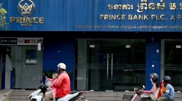 Motorists ride past a branch of the Prince Bank in Phnom Penh on October 15, 2025. A Cambodian bank founded by accused scam boss Chen Zhi, who has been indicted by the United States and extradited to China, was ordered liquidated on January 8, 2026, Cambodia's central bank said. Photo / TANG CHHIN Sothy / AFP