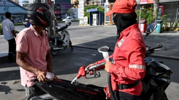 An employee (R) pumps gasoline into the vehicle of a customer at a gas station in Phnom Penh on March 9, 2026. Photo by TANG CHHIN SOTHY / AFP