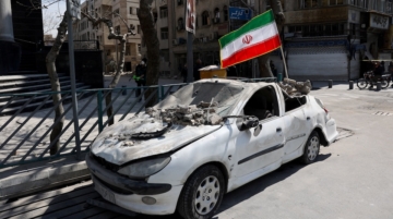 An Iranian flag is mounted on a damaged car following a strike on a police station, amid the U.S.-Israeli conflict with Iran, in Tehran, Iran, March 4, 2026. Majid Asgaripour/WANA via REUTERS