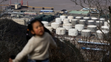 A child walks along a hiking trail with oil storage tanks and facilities of CNOOC Ningbo Daxie Petrochemical Co., Ltd. in the background in Ningbo, Zhejiang, China, March 21, 2026. REUTERS/Go Nakamura/File Photo