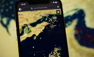 A smartphone displays the MarineTraffic app showing numerous ship beacons near the Strait of Hormuz with a satellite view in the background, in Creteil, France, on April 8, 2026. The United States and Iran have reached a diplomatic agreement reopening this strategic waterway to international maritime navigation. (Photo by Samuel Boivin/NurPhoto) (Photo by Samuel Boivin / NurPhoto via AFP)