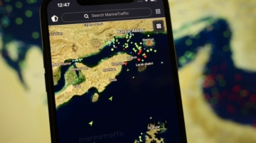 A smartphone displays the MarineTraffic app showing numerous ship beacons near the Strait of Hormuz with a satellite view in the background, in Creteil, France, on April 8, 2026. The United States and Iran have reached a diplomatic agreement reopening this strategic waterway to international maritime navigation. (Photo by Samuel Boivin/NurPhoto) (Photo by Samuel Boivin / NurPhoto via AFP)
