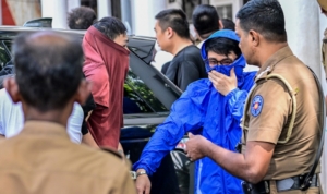 Prison guards escort foreign nationals to a court in Kaduwela, a suburb of Colombo, on May 7, 2026 after their arrest on suspicion of running cyberscam centers. Sri Lanka police arrested 231 foreign nationals, mostly Chinese and Vietnamese, following raids on three suspected cyberscam centres in the capital since the weekend, officials said on May 7. In Sri Lanka, authorities cracked down on two suspected cybserscam centres on May 3, arresting 37 and 120 people respectively. (Photo by Ishara S. KODIKARA / AFP)